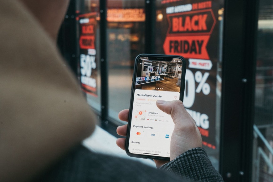 Someone looking at their phone for a sale while Black Friday shopping